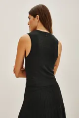 Top sin mangas con cuello halter, confeccionado en tejido de punto con acabado metalizado. Presenta un ajuste al cuerpo y diseño minimalista.