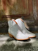 Botas cortas de cuero sintético color beige con detalles de costuras estilo western.