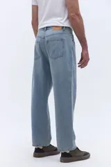 Pantalón de jean con corte baggy, tiro medio y diseño amplio en piernas y cadera. Cuenta con pasacintos y cierre frontal con botón.