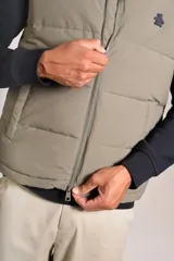 Chaleco puffer de corte regular, color beige, con cuello alto, cierre frontal completo y logo bordado en el pecho.