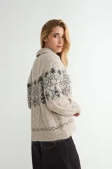 Saco de punto con cuello tipo polo, cierre frontal de botones oscuros y diseño de estampado jacquard en tonos grises y beige. Presenta mangas largas con puños acanalados y textura suave.