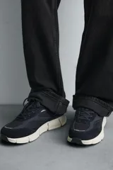 Zapatilla deportiva azul marino con detalles en gris oscuro y blanco. La parte superior está fabricada en combinación de piel con acabado serraje y tejido técnico transpirable. Cuenta con una suela ligera y voluminosa.