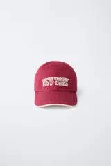 Gorra de béisbol azul marino con visera curva y detalle de borde en color crema. Presenta un bordado frontal con la palabra 'LONDON' en tipografía estilo varsity y texto adicional debajo.