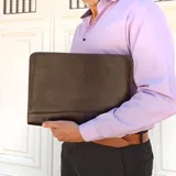 Sobre ejecutivo marrón oscuro de símil cuero con cierre alrededor. Cuenta con una repartición con fuelle para folios, tarjeteros, bolsillos y presilla para sujetar un block.