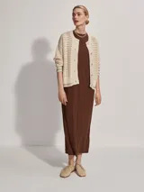 Cárdigan color crema de tejido de punto calado, con cuello redondo, cierre frontal con botones y corte holgado.