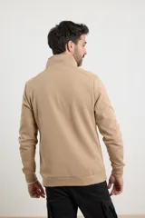 Cardigan de tejido de punto color verde militar, con cierre frontal de metal y cuello redondo. Presenta detalle de tejido plano en la cartera del cierre y en los bolsillos laterales.