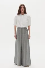 Camisa blanca de algodón con cuello mao, botonera oculta, mangas cortas estilo raglán con cortes estructurados y un bolsillo frontal con cierre.
