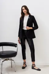 Pantalon negro de corte ajustado, confeccionado en una combinación de materiales que incluye paneles de efecto cuero en la parte frontal y trasera, con detalles de costuras horizontales en la zona de las rodillas.