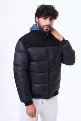Campera puffer negra con paneles de textura tipo corderito en la parte superior del pecho y hombros. Cuenta con cierre frontal, puños y ruedo acanalados, y un bolsillo vertical con cierre en el pecho.