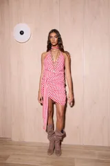 Vestido corto con diseño a rayas rojas y blancas, escote halter pronunciado, drapeado en la cadera y un lazo integrado que cuelga al costado.