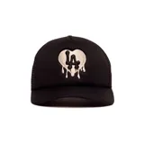 Gorro trucker negro con diseño frontal bordado que presenta un corazón blanco con efecto goteo y las letras "LA" en color negro.