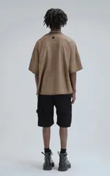 Remera de manga corta con calce extra oversize, color marrón chocolate con efecto gastado/deslavado. Presenta un corte con recortes horizontales en el frente y la espalda, y cuello redondo con terminación deshilachada.