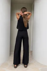Pantalón de lino de pierna ancha, color beige con franjas verticales blancas a los lados y lazo ajustable en la cintura.