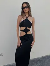 Vestido largo negro de lycra con escote halter y aberturas geométricas en la cintura.