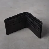 Billetera plegable de eco cuero azul, con múltiples compartimentos para tarjetas, monedero con cierre, tarjetero con visor y dos espacios para billetes. Presenta líneas de pespunte decorativas en la parte superior y el logo de la marca grabado en la esquina inferior.