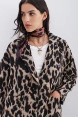 Tapado cruzado de corte oversize confeccionado en paño con estampado de leopardo. Presenta solapas clásicas, cierre frontal con botones y bolsillos aplicados.