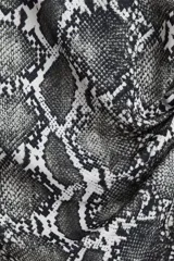 Top de punto suave con estampado de piel de serpiente en tonos grises y blancos, con mangas japonesas, cuello redondo y frunces laterales que crean un efecto drapeado.