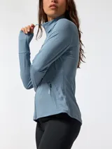 Campera deportiva de segunda capa confeccionada en tejido suave melange color celeste. Cuenta con cuello alto, cierre frontal completo, bolsillos laterales con cierre y orificios para los pulgares en los puños.