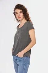 Remera color beige con cuello redondo, mangas cortas, bolsillo pequeño en el pecho y media botonadura frontal.