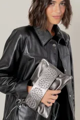 Sobre de mano confeccionado en cuero vacuno metalizado color plata, con solapa frontal decorada con múltiples ojales metálicos. Cuenta con cierre principal y bolsillo trasero con cierre.