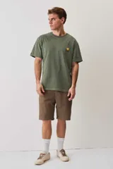 Remera de calce relajado y cuello redondo, color verde musgo con efecto lavado, y pequeño bordado de un morrón en el pecho.