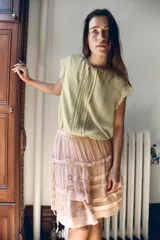 Falda corta de tiro bajo confeccionada en viscosa, con diseño de volantes superpuestos y frunces. Presenta detalle de lazadas laterales ajustables y cierre lateral con cremallera oculta.