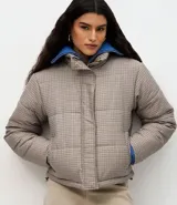 Campera puffer Marfinno con estampa de cuadros mini en tonos beige y negro, de corte recto, cuello alto y cierre frontal con cremallera. Cuenta con mangas largas y forro interior.