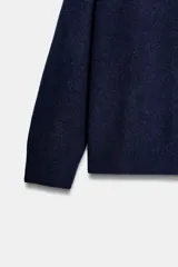 Jersey de punto liso color azul marino, con cuello redondo y manga larga. Acabados en rib.