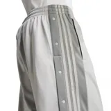 Pantalón deportivo gris claro de corte recto con cintura elástica y cordón ajustable. Presenta las tres líneas características de Adidas en gris oscuro a lo largo de la pierna y botones a presión en los laterales.