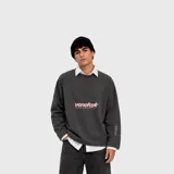 Buzo gris oscuro de corte holgado, con cuello redondo y mangas largas. Presenta un estampado frontal con la inscripción "venefox ANYWHERE, EVERYWHERE" y una estrella en tonos rosados, además de texto lateral en la manga.