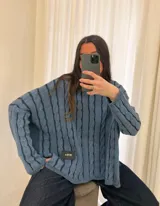 Sweater de punto con diseño de rayas verticales en relieve y textura trenzada, color terracota y beige. Presenta cuello redondo, corte holgado y diseño cropped.