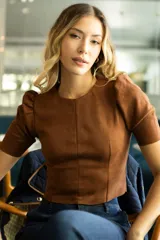 Top corto color verde militar, marca Tahari, confeccionado en símil gamuza. Tiene mangas cortas abullonadas, cuello redondo y cierre invisible en la espalda.