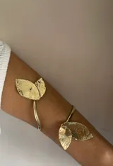 Brazalete dorado para el brazo, con forma de hojas texturizadas.