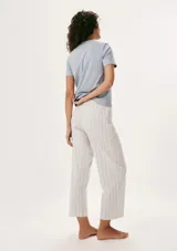 Pijama compuesto por una remera de manga corta color celeste con estampa frontal y un pantalón largo de corte recto con estampado de rayas verticales en tonos neutros.