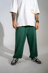 Pantalón de jogging verde oscuro con corte holgado, cintura elástica con cordón de ajuste y bolsillos laterales.