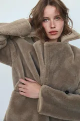 Abrigo reversible de corte recto con cuello solapa, manga larga y cierre frontal de doble botonadura. Presenta un diseño de efecto pelo en un lado y efecto piel en el reverso, con bolsillos de plastrón en el frente.