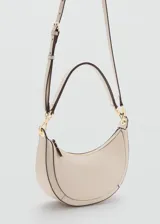 Bolso de mano y hombro de diseño semi-circular en color beige, con herrajes metálicos dorados, cierre superior de cremallera y correa ajustable desmontable.