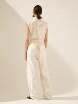 Mono color verde oliva, con cuello camisero, sin mangas, bolsillos frontales y laterales tipo cargo, y cinturón de lazo.