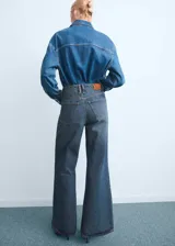 Pantalón de jean estilo wide leg con tiro alto, confeccionado en tejido de algodón. Presenta diseño de cinco bolsillos, cierre de botones y trabillas para cinturón.