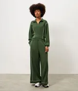 Pantalón deportivo ancho de color verde oscuro, de talle alto con cintura elástica y detalles de vivos en color blanco en los laterales y la botamanga.