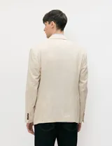 Blazer beige de medio forro confeccionado en mezcla de algodón y lino, con silueta estructurada, solapas de muesca, cierre frontal de dos botones y bolsillos con solapa.