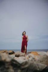 Vestido largo color borgoña con brillos, de corte ajustado, con cuello halter y abertura en la pierna.