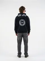 Hoodie negro con capucha, diseño estampado en la espalda con el logo de la marca dentro de un círculo de laureles y texto en la parte posterior de la capucha.