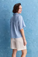 Blusa celeste de manga corta con cuello camisero y escote en V, confeccionada en tejido liviano con textura sutil y estampado de lunares.