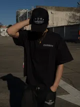 Remera negra oversize de manga corta, con estampa tipográfica vertical en la espalda y logo pequeño en el frente.
