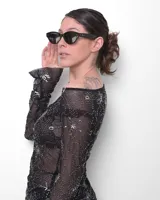 Anteojos de sol negros con montura de acetato premium y forma de ojo de gato. Los cristales son oscuros y polarizados con filtro UV 400. Presentan pequeños remaches decorativos en la parte frontal superior y un logo grabado en la patilla derecha.