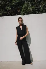 Top sin mangas confeccionado en tejido piqué, con escote cruzado tipo solapa y detalle de pliegues. Presenta una banda ancha ajustada en la cintura y un diseño de hombros caídos.