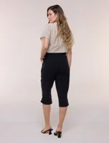 Pantalón capri negro de calce relajado y pierna recta, confeccionado en algodón. Posee cintura elastizada con cordón ajustable, bolsillos delanteros y detalle de presilla con botón en los ruedos.