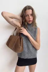 Top sin mangas de punto con mezcla de lana y alpaca, color gris jaspeado. Presenta cuello subido y detalle de abalorios joya en los hombros.