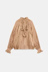 Camisa satinada color tostado con cuello alto fruncido, mangas largas amplias y puños elásticos con volados.